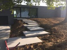 concrete steps leading up to a building with trees in the foreground and dirt on the ground