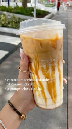 a woman holding up a cup with caramel drizzle on it's side