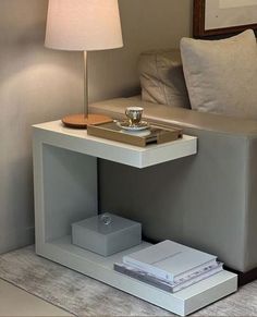 a white table with a lamp and some books on it