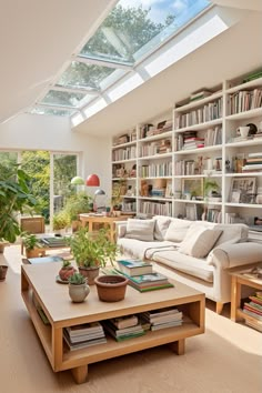 a living room filled with lots of furniture and bookshelves under a skylight