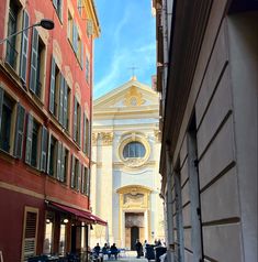 an alley way with tables and chairs in front of a church