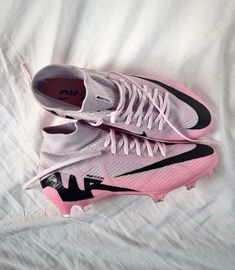 a pair of pink and black shoes sitting on top of a white sheet