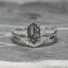 an engagement ring with a large stone surrounded by smaller stones and diamonds on top of it