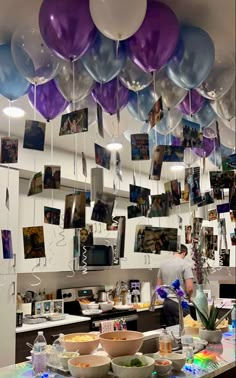 balloons and pictures hang from the ceiling in a kitchen