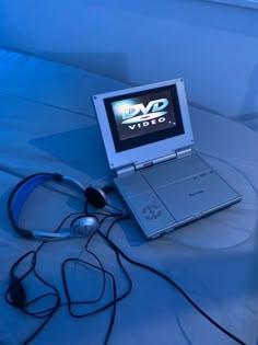 a laptop computer sitting on top of a bed next to headphones and ear buds