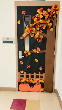 a door decorated with fall leaves and an autumn tree on the front entrance to a building