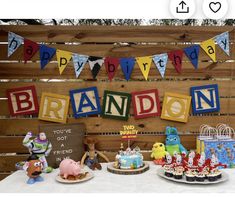 a birthday party with cupcakes, cakes and decorations on a table in front of a wooden fence