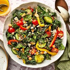 a white bowl filled with lots of vegetables on top of a table next to utensils