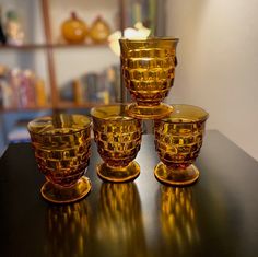 four golden glass cups and saucers sitting on a table