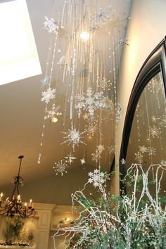 a chandelier hanging from the ceiling next to a mirror with snowflakes on it