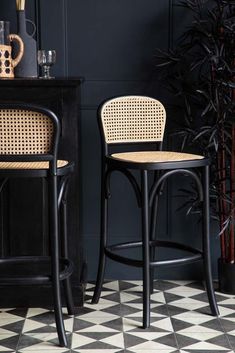 two black and white stools sitting next to each other on a checkered floor