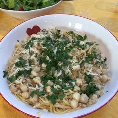 a white bowl filled with pasta and garnished with parsley on the side