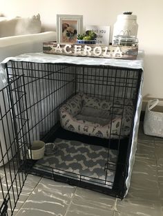 a dog crate with a bed in it and some pictures on the top shelf above