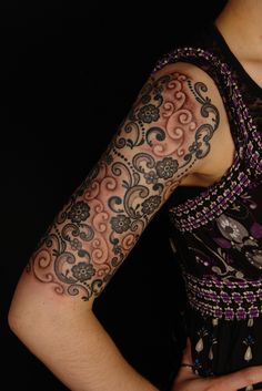 a woman with tattoos on her arm holding a cell phone