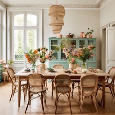 a dining room table with chairs and vases on it