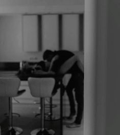 a man sitting at a kitchen table in front of a laptop computer on top of a counter