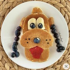 a plate topped with pancakes and blueberries on top of a woven place mat next to a straw basket