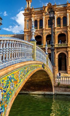 an ornate bridge over a river in front of a large building