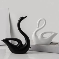 two black and white swan figurines sitting next to each other on a table