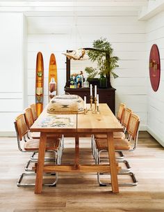 a dining room table and chairs with surfboards in the background