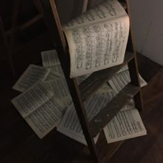 an old wooden ladder with lots of books on it and some papers falling from the top