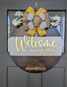 a welcome to our place of heaven sign on the front door of a building with flowers and an open book