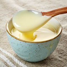 a wooden spoon in a blue bowl filled with yogurt on a tablecloth