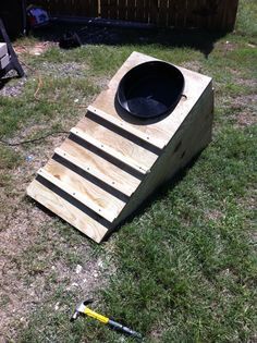 a large wooden bowl sitting on top of a grass covered field next to a tool