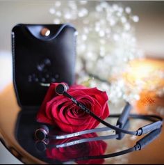 a red rose sitting on top of a table next to a pair of headphones