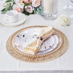 a table set with plates, napkins and flowers