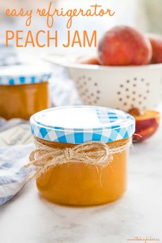 two jars filled with peach jam sitting on top of a table next to some apples