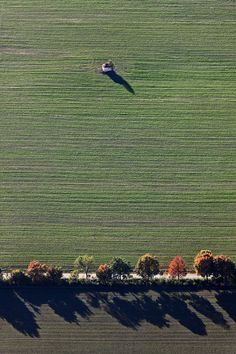 an airplane flying over a green field with trees