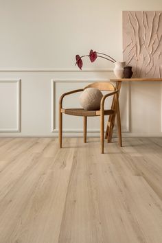 a chair sitting on top of a hard wood floor next to a table with vases