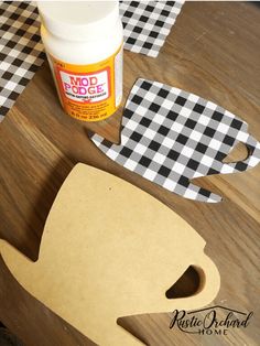 a wooden table topped with paper cutouts next to a jar of glue and scissors