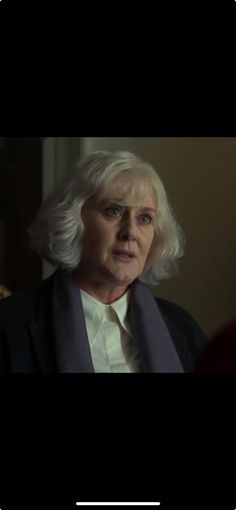 an older woman with white hair wearing a suit and tie