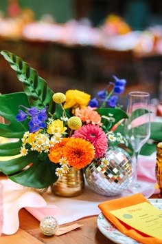 pink flowers are in a silver vase next to a glass of water on a table