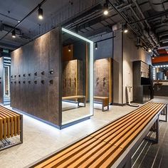 an empty room with wooden benches and lockers in it's center area, surrounded by metal partitions