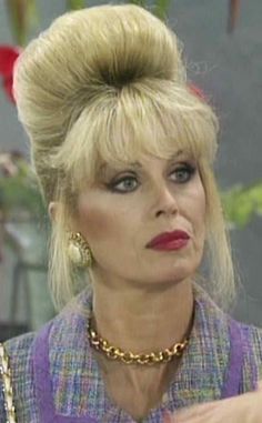 a woman with blonde hair wearing a purple top and gold necklace on the set of tv show