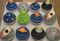 a box filled with lots of cupcakes covered in frosting and space themed decorations