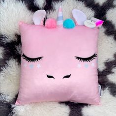 a pink unicorn pillow with eyelashes and stars on it