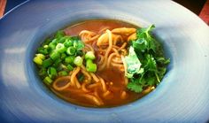 a blue bowl filled with noodles and veggies