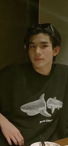 a young man sitting at a table with a plate of food in front of him