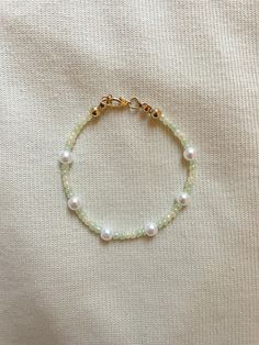 a white beaded bracelet with pearls and gold beads on a white cloth covered surface