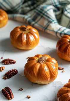 several pumpkins and pecans on a white surface with a plaid napkin in the background