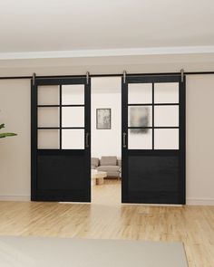 an open living room with black doors and wood flooring on the wooden floor next to a couch