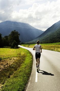 a man is running down the road with mountains in the background