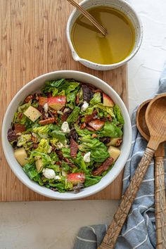 a white bowl filled with salad next to a wooden spoon and cup of green tea