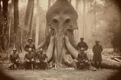 an elephant is sitting in the middle of a forest with men and dogs around it