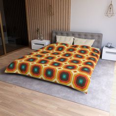 a bed with an orange and green bedspread on it in a bedroom next to a wooden floor