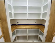 an empty room with white shelves and wood flooring